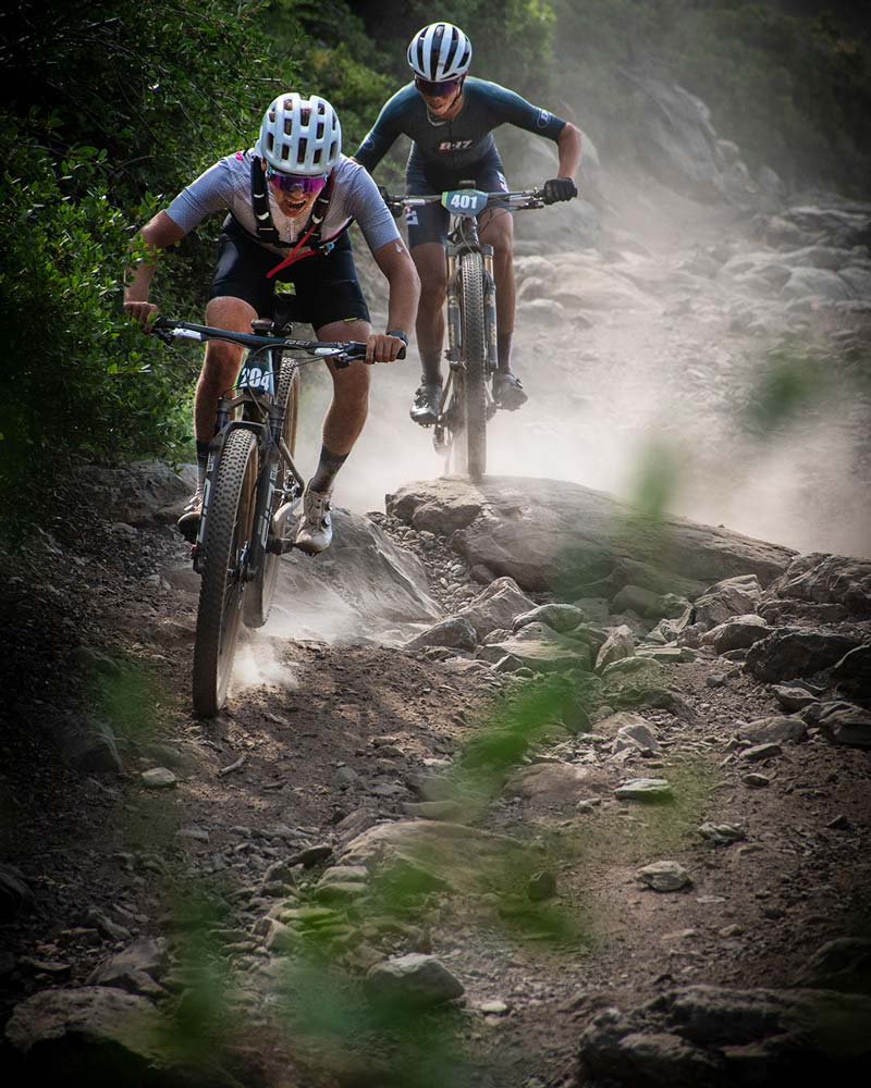 mountain bike racers jumping over rocks